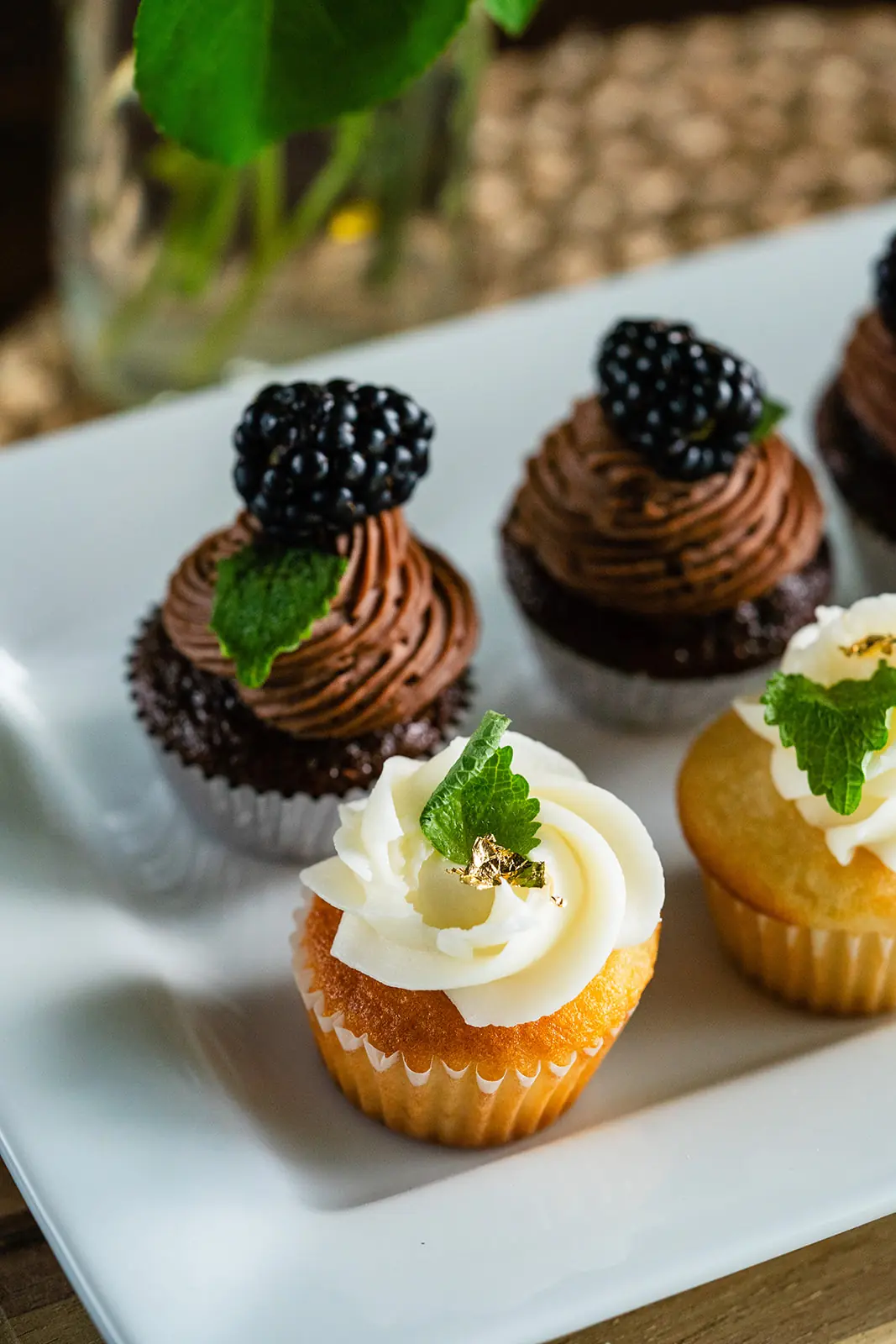 Mini cupcakes with blackberries, mint, and a gold-leafed vanilla rose swirl