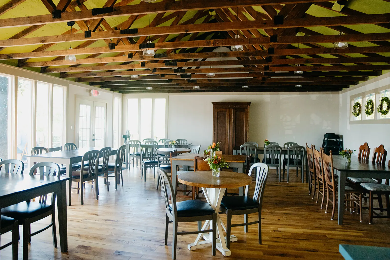 The Green Room at Humble Crumb, with a bright green open-rafter ceiling, hardwood floors, and tables facing the patio doors