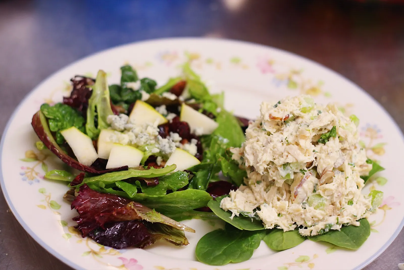 A floral plate with mixed green salad and a scoop of chicken salad