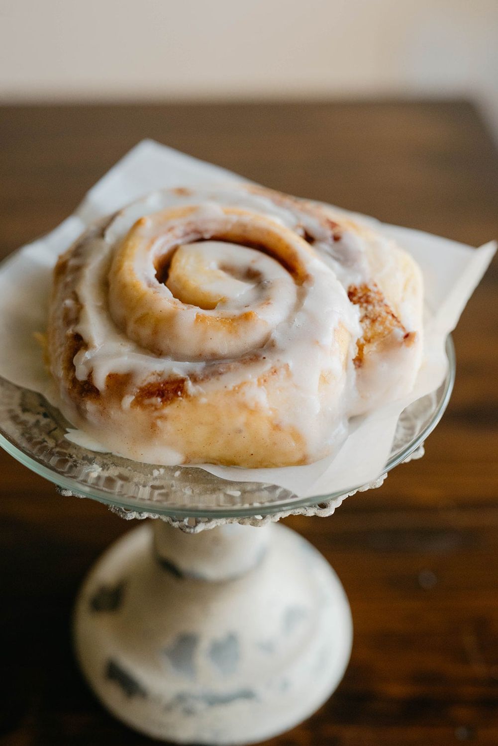 A freshly iced Humble Crumb cinnamon roll on a cake stand