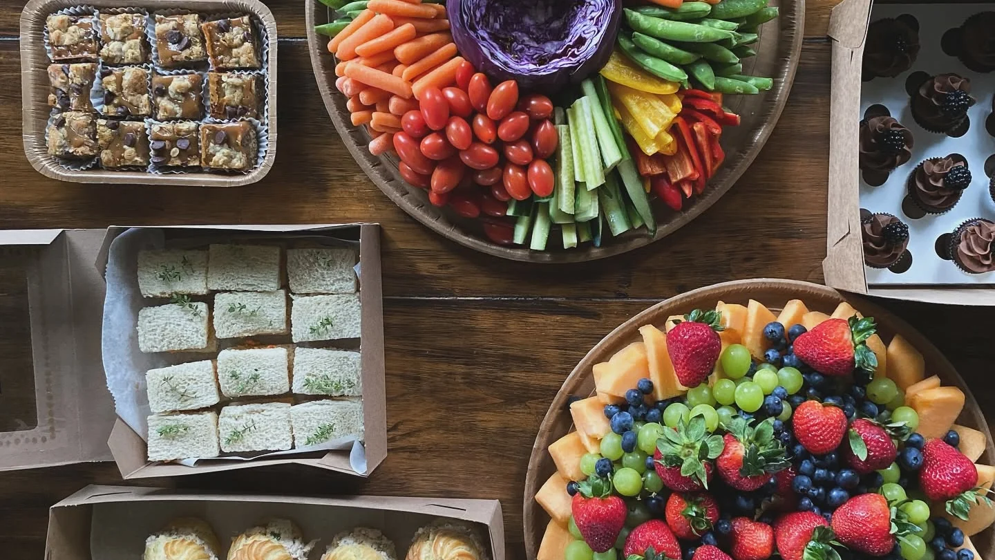 Catering spread with sandwiches, fruit, vegetables, and desserts