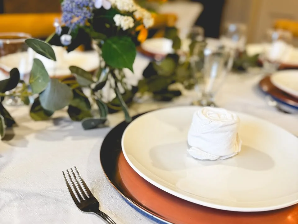 Close view of a formal Humble Crumb event place setting with flowers